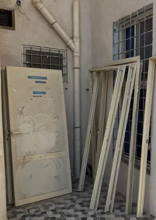 باب وإطارات ألمنيوم مسندة إلى جدار في فناء