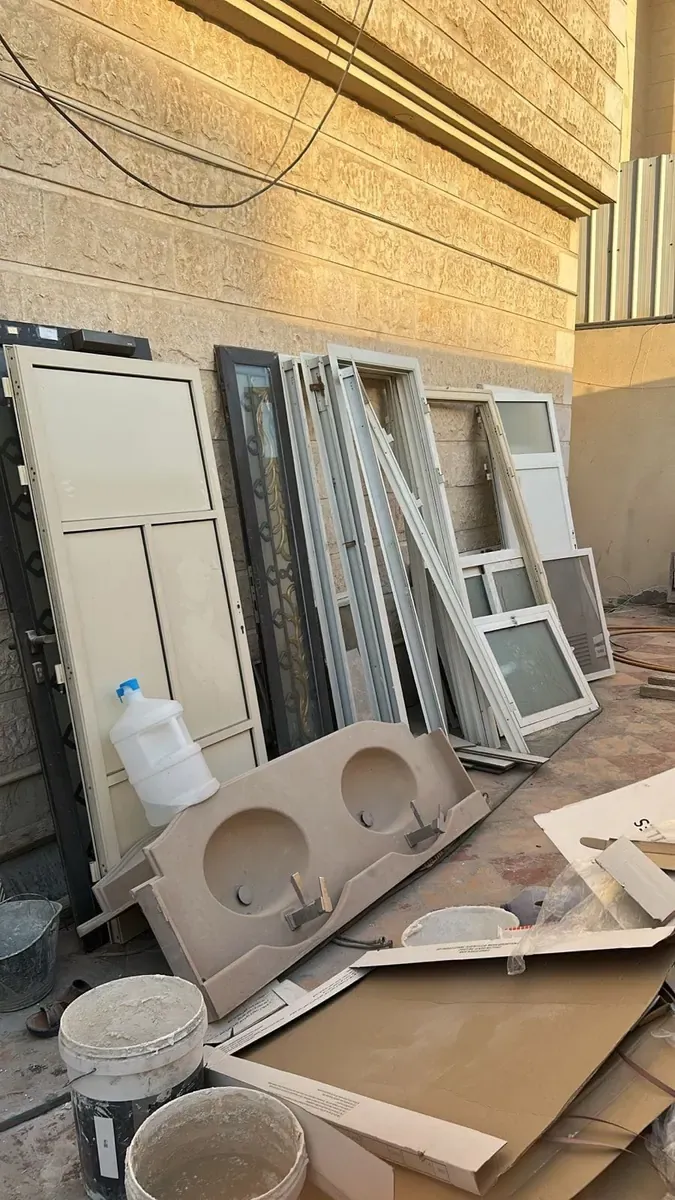 أبواب ونوافذ ألمنيوم وقاعدة مغسلة مكدسة في الخارج