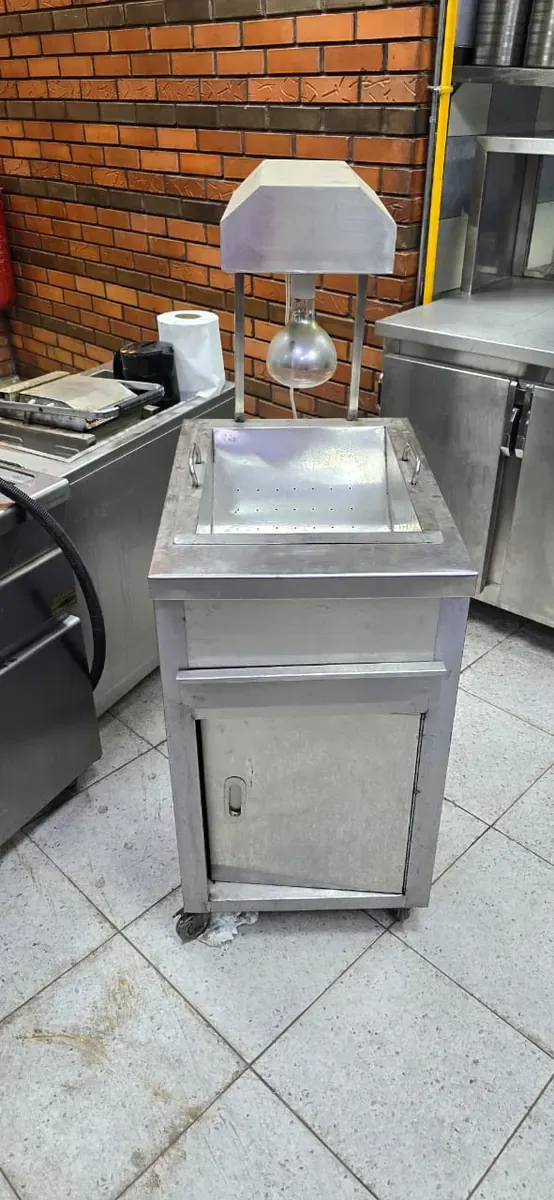 عربة ستانلس صغيرة بمصباح تسخين أمام جدار طوب